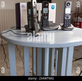 BT schnurlose analoge Telefone mit Basisstation, Anrufsperre, Anrufbeantworter, die Pappschachtel, die sie auf einem hellblauen Tisch fanden Stockfoto