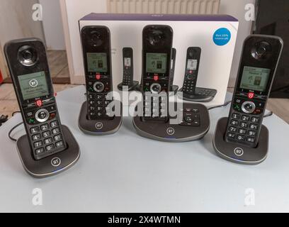 BT schnurlose analoge Telefone mit Basisstation, Anrufsperre, Anrufbeantworter, die Pappschachtel, die sie auf einem hellblauen Tisch fanden Stockfoto