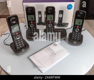 BT schnurlose analoge Telefone mit Basisstation, Anrufsperre, Anrufbeantworter, die Pappschachtel, die sie auf einem hellblauen Tisch fanden Stockfoto