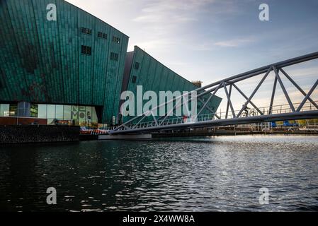 NEMO Science Museum, das in den Hafen ragt und eine Fußgängerbrücke aus Stahl über einen Kanal in Amsterdam, Niederlande. Stockfoto