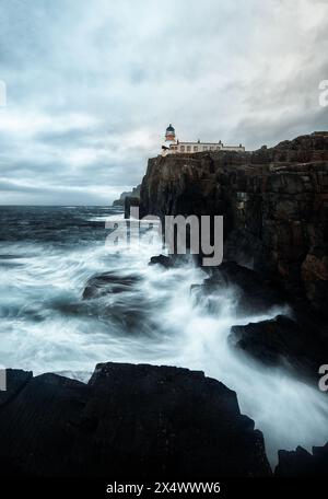 Neist Point Lighthouse – wilde Wellen krachen gegen die zerklüfteten Klippen und senden Schaum in die Luft, als ob man versuchen würde, den Leuchtturm zu erreichen. Stockfoto