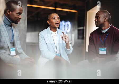 Drei Business Professionals führen auf einer Konferenz-expo eine konzentrierte Diskussion. Sie wirken sachkundig, selbstbewusst und kooperativ. Stockfoto