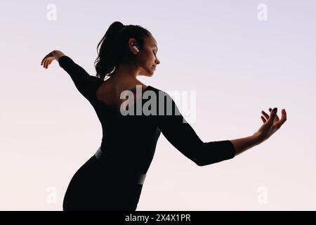 Selbstbewusste, junge Tänzerin zeigt künstlerischen Ausdruck mit dynamischen Tanzbewegungen und flexibler Körpersprache. Stockfoto