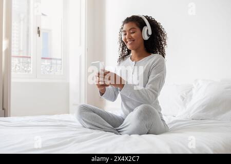Junge Frau, Die Musik Mit Kopfhörern Genießt, Während Sie Auf Dem Smartphone Surft Stockfoto
