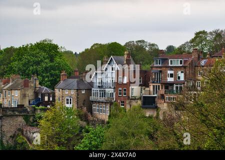 Malerischer Blick auf traditionelle britische Häuser auf einem Hügel, umgeben von üppigem Grün im Frühling. Stockfoto