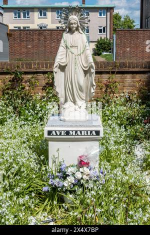 Eine Marienstatue, Mutter Jesu mit dem Titel „Ava Maria“ oder „Heil Maria“ steht vor einer katholischen Kirche Stockfoto