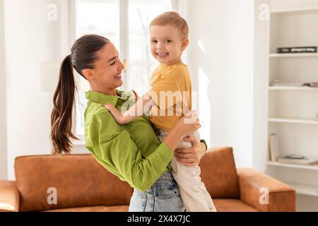 Frau, die Kind in den Armen hält, zu Hause kuschelt Stockfoto