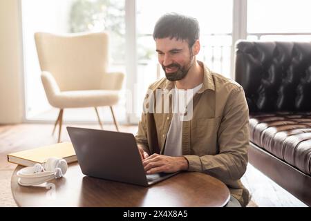 Mann, der einen Laptop am Tisch zu Hause benutzt Stockfoto