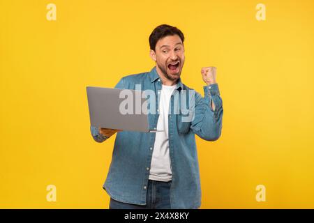 Mann feiert Erfolg mit Laptop, Gesten und Ausflügen Stockfoto