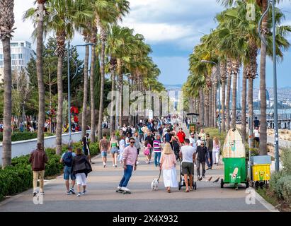 Menschenmassen laufen entlang der palmengesäumten Promenade, Limassol, Zypern Stockfoto