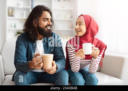 Mann und Frau sitzen auf einer Couch und halten Kaffeetassen Stockfoto