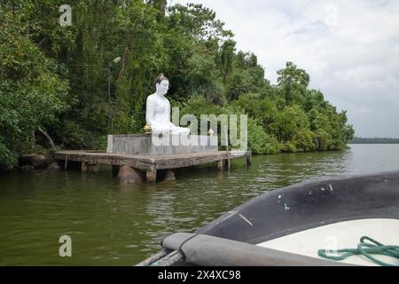 Beruwala, Sri Lanka. Am 7. februar 2023 sitzt die weiße Buddha-Figur über dem See. Hintergrund wunderschöne Naturpalmen, blauer Himmel. Asien Reisen und Religion Co Stockfoto