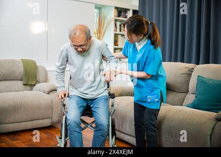 Asiatischer Arzt unterstützt alten Mann beim Aufstehen für Bewegung Stockfoto