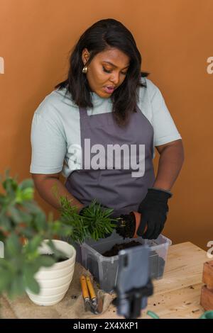 Ein afroamerikanischer Florist-Blogger filmt ein Tutorialvideo über die Pflanzung von Pflanzen im Heimgarten. Video-Vlog mit Mobiltelefon erstellen Stockfoto