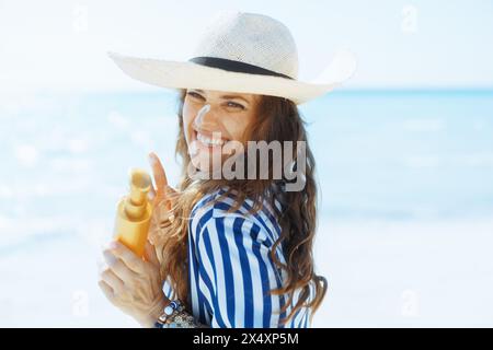 Glückliche elegante Frau an der Küste mit Sonnencreme. Stockfoto