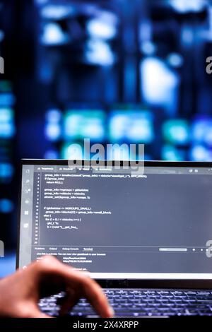 Computerwissenschaftler aktualisieren Rackhalterungen, schreiben Codezeilen auf Laptop-Terminal, Nahaufnahme. Mitarbeiter verwenden JavaScript, Java und Datenbankprogrammierung, um ein nahtloses Server-Farm-Computing zu gewährleisten Stockfoto