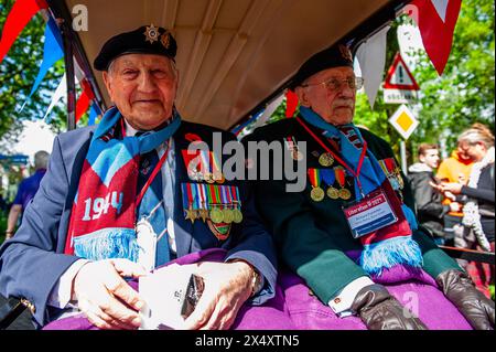 Wageningen, Niederlande. Mai 2024. Zwei Veteranen des Zweiten Weltkriegs werden während der Parade beim Lächeln des Publikums beobachtet. Während des Befreiungstages findet die Befreiungsparade (Bevrijdingsdefilé) statt, die Veteranen und militärische Nachfolger zusammenführt, um all jenen zu würdigen, die während des Zweiten Weltkriegs ihr Leben gaben, und der internationalen militärischen Zusammenarbeit. An der Front der Parade standen zwölf britische Veteranen, die im Zweiten Weltkrieg für die Freiheit der Niederlande kämpften. Quelle: SOPA Images Limited/Alamy Live News Stockfoto