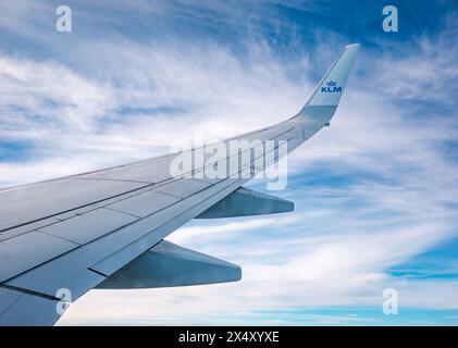 Blick vom KLM-Flugzeugfenster auf den Flugzeugflügel gegen Wolken und Himmel Stockfoto