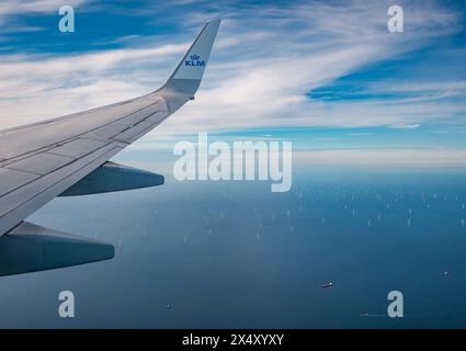 Blick vom KLM-Flugzeugfenster auf den Flugzeugflügel und den Windpark in der Nordsee vor der niederländischen Küste Stockfoto