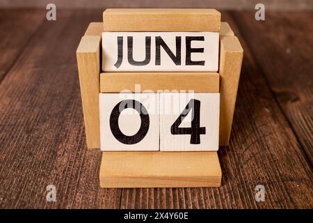 Kreidetafel mit Kalenderdatum Juni 04 auf weißem Würfel auf Holztisch Stockfoto