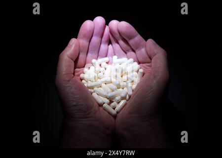 Ein Paar Hände, die Tabletten in Form eines Herzens halten Stockfoto