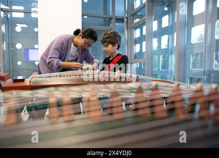 Belgrad, Serbien. April 2024. Eine Lehrerin hilft ihrem Schüler, vor einem Guzheng-Kurs im China Cultural Center in Belgrad (Serbien) am 29. April 2024 falsche Nägel zu tragen. Das China Cultural Center in Belgrad, das gemeinsam vom chinesischen Ministerium für Kultur und Tourismus und der Provinzregierung von Shandong errichtet wurde, wurde kürzlich für die Öffentlichkeit geöffnet. Das Zentrum erstreckt sich über eine Fläche von 6.000 Quadratmetern und bietet Kurse in chinesischer Sprache, traditionellen chinesischen Musikinstrumenten, chinesischer Kalligraphie und Tai Chi an. Quelle: Li Jing/Xinhua/Alamy Live News Stockfoto