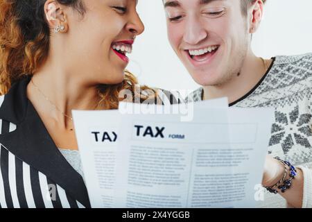 Mann und Frau teilen einen unbeschwerten Moment, während sie Steuerdokumente überprüfen, scheinbar ohne die finanzielle Belastung Stockfoto