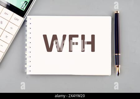 WFH Work from Home Text Concept. WFH auf einem weißen Notizbuch auf grauem Hintergrund Stockfoto