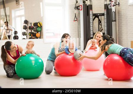 Bewegungsklasse für Babys. Eltern helfen Babys, die motorischen Fähigkeiten zu verbessern, die richtige Bewegung auf dem Fitball. Pädiatrie Physiotherapeut in der Spitzenklasse. Mütter Stockfoto