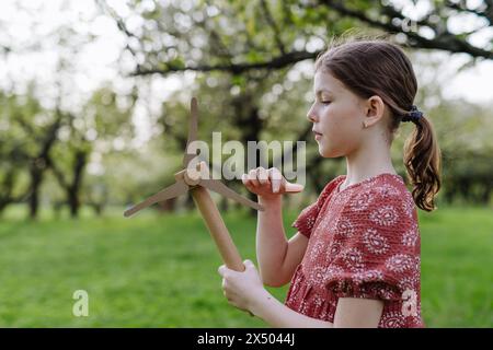 Mädchen, das draußen im Park steht und Windkraftanlage hält. Erneuerbare Windenergie und nachhaltige Lebensweise. Stockfoto