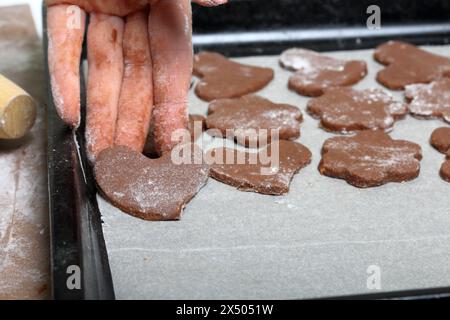 Eine Frau legt die Rohlinge für Lebkuchen auf ein Backblech. Bemehlt. Lebkuchen kochen. Stockfoto