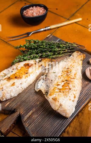Rotes Meerbarschfilet, Rotbarsch auf Holzbrett. Orangefarbener Hintergrund. Draufsicht. Stockfoto