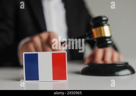 Die Hand des Richters hält einen Holzhammer. Flagge von Frankreich. Das Konzept der französischen Justiz Stockfoto