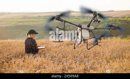 Frau Farmer kontrolliert die Drohnenspritze mit einer Tablette. Intelligente Landwirtschaft und präzise Landwirtschaft Stockfoto