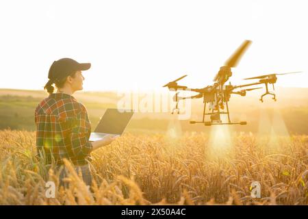 Frau Farmer kontrolliert die Drohnenspritze mit einer Tablette. Intelligente Landwirtschaft und präzise Landwirtschaft Stockfoto
