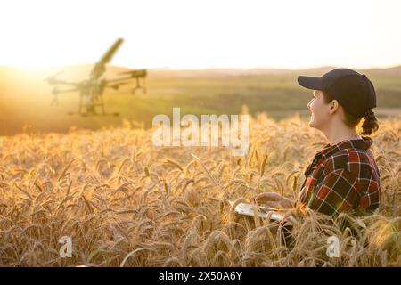 Landwirtin steuert Drohnensprühgerät mit einem Tablet. Intelligente Landwirtschaft und Präzisionslandwirtschaft. Stockfoto