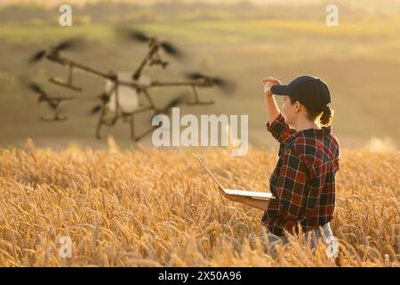 Landwirtin steuert Drohnensprühgerät mit einem Tablet. Intelligente Landwirtschaft und Präzisionslandwirtschaft. Stockfoto