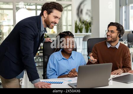 Glückliche Geschäftsleute, die im Büro an einem neuen Projekt auf Laptop arbeiten Stockfoto