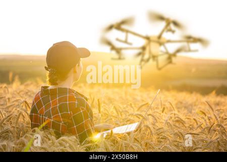 Frau Farmer kontrolliert die Drohnenspritze mit einer Tablette. Intelligente Landwirtschaft und präzise Landwirtschaft Stockfoto