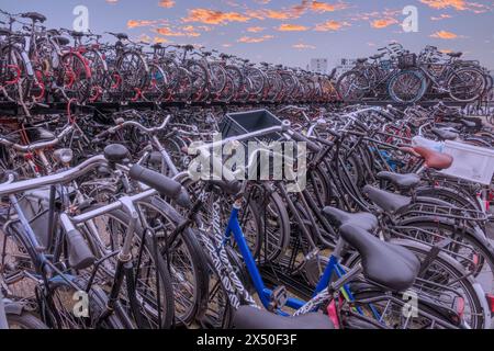 Niederlande. Viele Fahrräder in einem zweistöckigen Fahrradparkplatz in der Nähe des Amsterdamer Hauptbahnhofs und einem herrlichen Sonnenuntergangshimmel Stockfoto