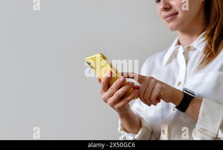 Junge Geschäftsfrau, die Online-Nachrichten über ihr Smartphone sendet. Touchscreen des Telefons mit dem Finger. Stockfoto