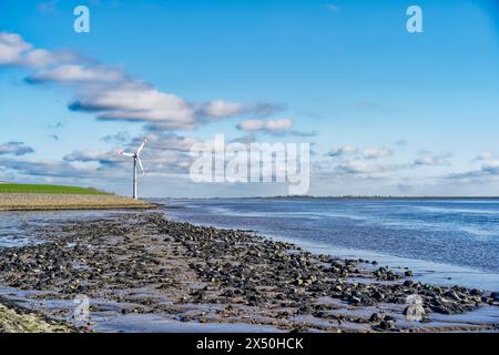 Windkraftanlage am Ufer der Ems bei Ebbe, Ostfriesland, Niedersachsen, Deutschland Stockfoto