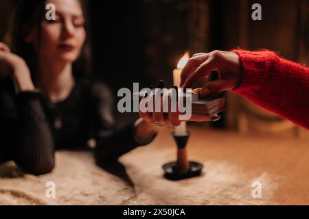 Nahaufnahme zugeschnittene Aufnahme von mysteriösen Wahrsagern, die Tarotkarten mischen und weibliche Klientin bitten, Kartenstapel für das Layout während der Sitzung in zu verschieben Stockfoto