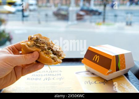 Der Mann isst in McDonald's Restaurant. McDonald's Fast-Food-Restaurant. Der Mann isst Burger Big mac mit der Hand. Minsk, Weißrussland - 15. August 2022 Stockfoto