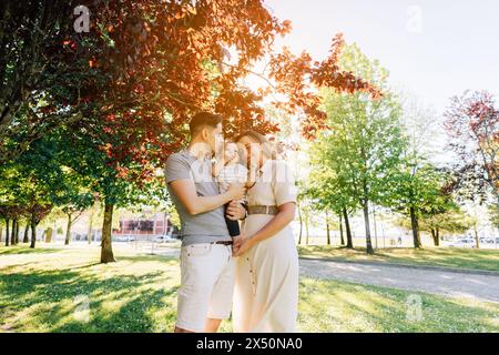 Porträt einer jungen Familie mit ihrem neunmonatigen Baby, das sich im öffentlichen Park amüsiert Stockfoto