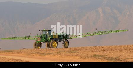 Westkap, Südafrika. April 2024. Traktor mit Auslegerarmen verlängertes Spritzen von Wasser, bevor eine Bohrmaschine Rapssamen auf fa pflanzt Stockfoto