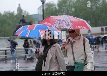 Die Menschen schützen sich vor dem Regen unter Regenschirmen, während sie in der Nähe des Buckingham Palace im Zentrum von London spazieren. Wettervorhersagen haben gewarnt, dass Gewitter und starke Regenfälle am Montag zu Überschwemmungen und Reisestörungen führen können. Bilddatum: Montag, 6. Mai 2024. Das Foto sollte lauten: Yui Mok/PA Wire Stockfoto