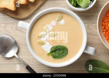 Gesunde Cremesuppe mit hohem Gehalt an pflanzlichen Fetten auf Holztisch serviert, flach gelegt Stockfoto