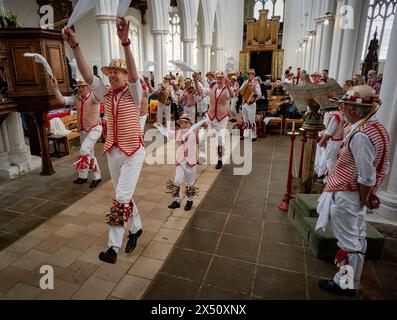 Thaxted, England Gb Mai 2024. Thaxted Essex UK May Day Morris Dancing in Thaxted Church 6 Mai 2024 Thaxted Morris Side (Red and White Stripes) und Blackmoore Morris Side in Blue spielen ungewöhnlich ihren traditionellen May Day Morris Dancing Set in der Thaxted Church aufgrund des schlechten Maiday Wetters. Conrad Noel (12. Juli 1869 bis 22. Juli 1942), ein christlicher Sozialist, bekannt als der „Rote Vikar“ von Thaxted, half zusammen mit Cecil Sharp, 1934 bei der Wiedergründung des Morris-Rings in Thaxted Credit: BRIAN HARRIS/Alamy Live News Stockfoto