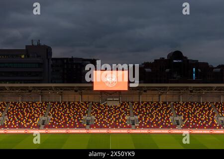 Dämmerungsansicht über das Spielfeld mit einem großen fernsehbildschirm. Brentford Community Stadium, Brentford, Vereinigtes Königreich. Architekt: AFL Architects, 2020. Stockfoto